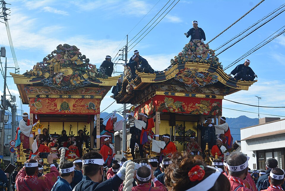 Two ornate floats pass during daytime activities of the Chichibu Night Festival in December 2022.